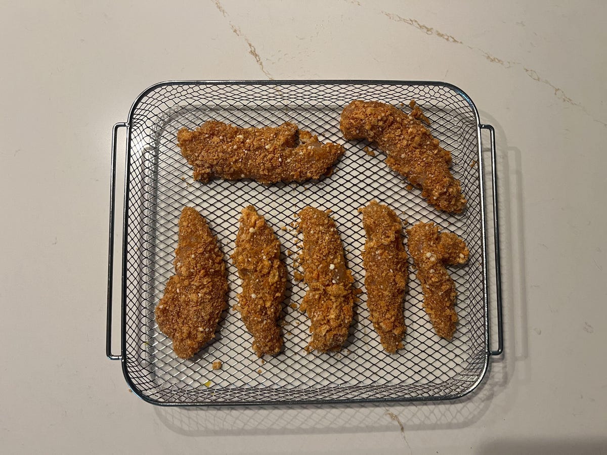 chicken fingers breaded and laid out on air fryer basket